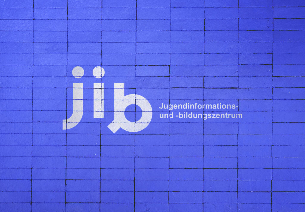 Auf dem Foto ist eine blaue Steinmauer mit dem Logo des Jugend- und Informationszentrums, kurz jib, in Münster zu sehen.